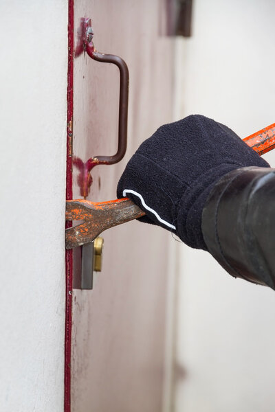 Burglar wearing leather coat breaking in a house