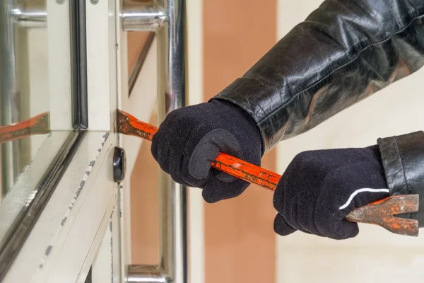 Burglar wearing leather coat breaking in a house — Stock Photo, Image