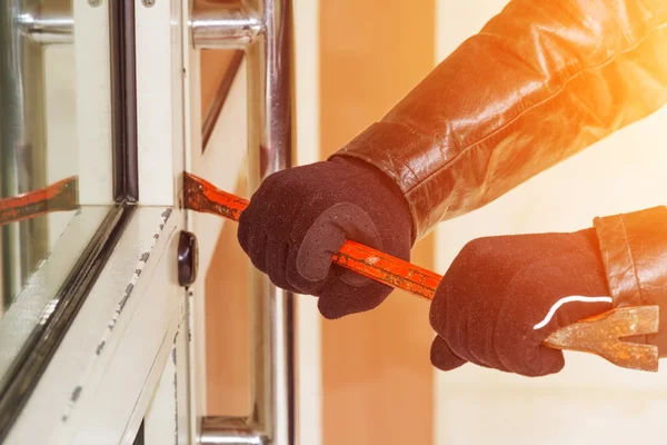 Burglar wearing leather coat breaking in a house — Stock Photo, Image