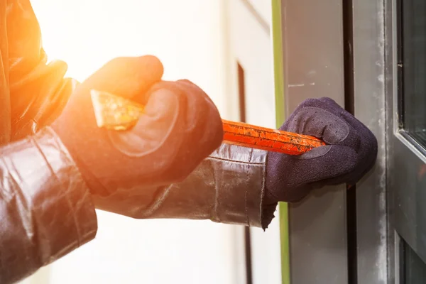 Inbreker dragen van leren jas breken in een huis — Stockfoto