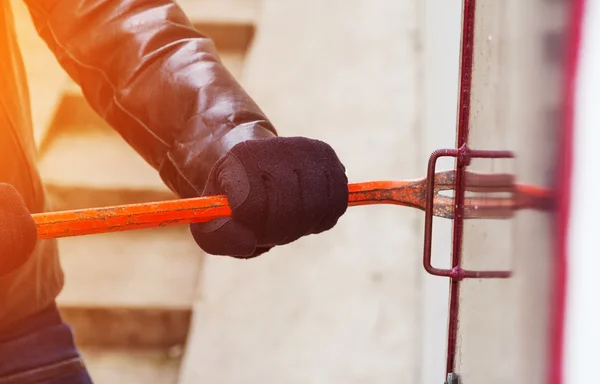 Burglar wearing leather coat breaking in a house — Stock Photo, Image