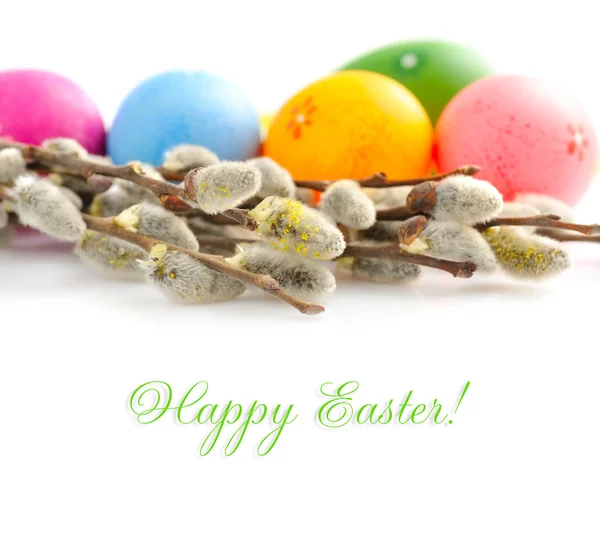 Barevné velikonoční vajíčka a větve vrby na bílém pozadí — Stock fotografie