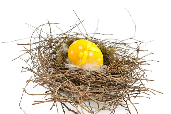 Un huevo amarillo de Pascua en el nido sobre un fondo blanco —  Fotos de Stock