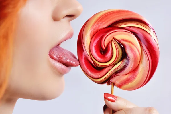 Close-up of a beautiful girl licking a colorful lollipop — Stock Photo, Image