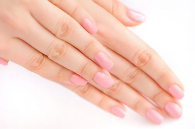 Elinde çivi beyaz arka plan üzerinde pembe manikür genç bir kadınla closeup