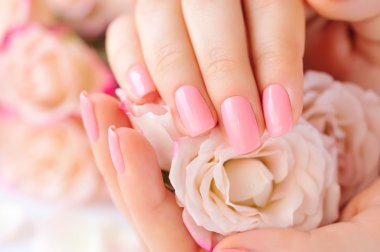 Elinde çivi ve gül pembe manikür olan bir kadın