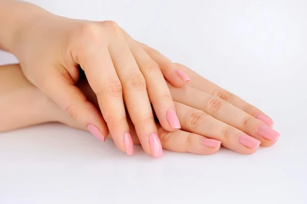 Close-up de mãos de uma jovem mulher com manicure rosa em pregos contra fundo branco — Fotografia de Stock