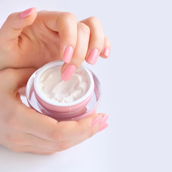 Las manos de una mujer con manicura rosa con crema — Foto de Stock