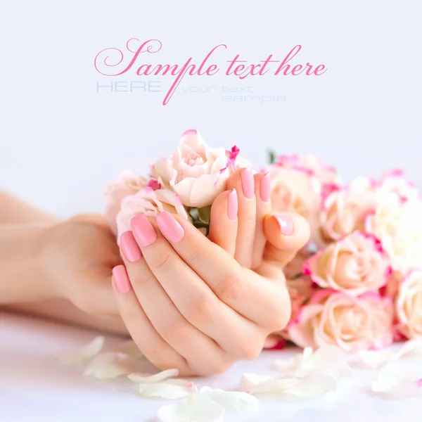 Handen van een vrouw met roze manicure nagels en rozen — Stockfoto