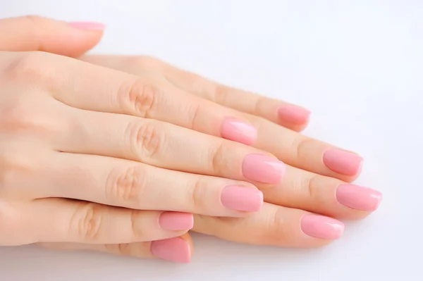 Gros plan des mains d'une jeune femme avec manucure rose sur les ongles sur fond blanc — Photo