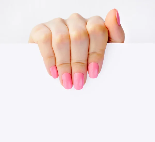 Mão de uma mulher com manicure rosa segurando papel branco vazio — Fotografia de Stock