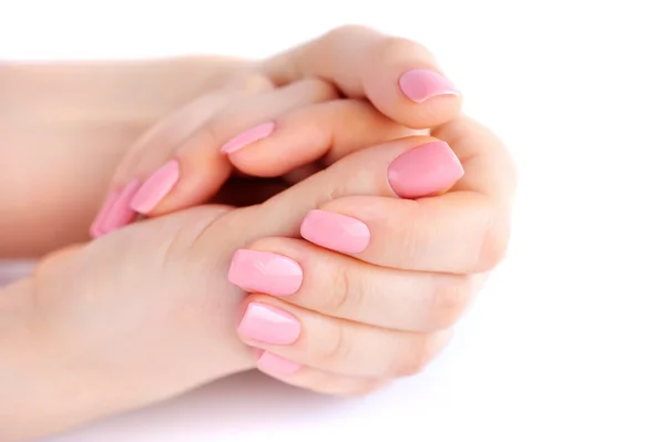 Gros plan des mains d'une jeune femme avec manucure rose sur les ongles sur fond blanc — Photo