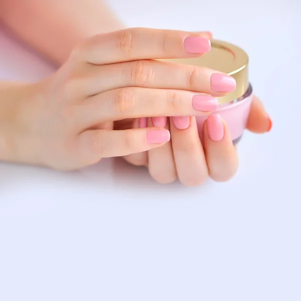 Mãos de uma mulher com manicure rosa com creme — Fotografia de Stock