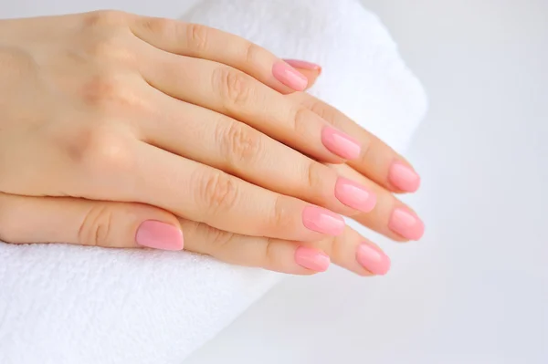 As mãos de uma mulher com manicura rosa estão em uma toalha — Fotografia de Stock