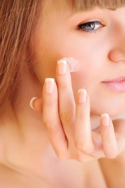 Volto di bellezza di donna giovane con crema cosmetica su una guancia. Pelle — Foto Stock