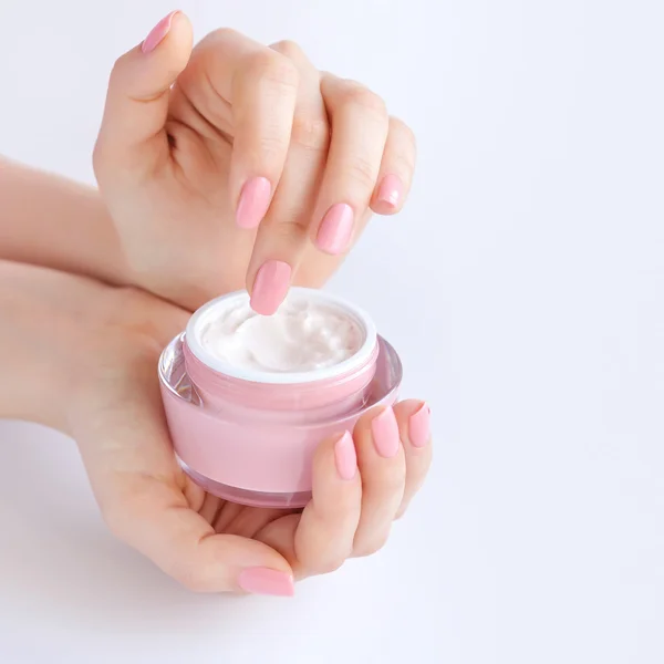 Las manos de una mujer con manicura rosa con crema — Foto de Stock