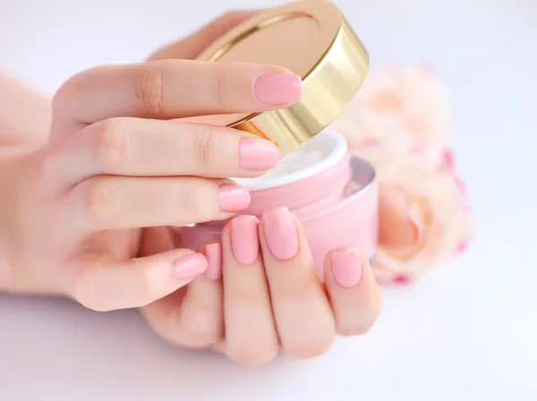 Las manos de una mujer con manicura rosa con crema —  Fotos de Stock