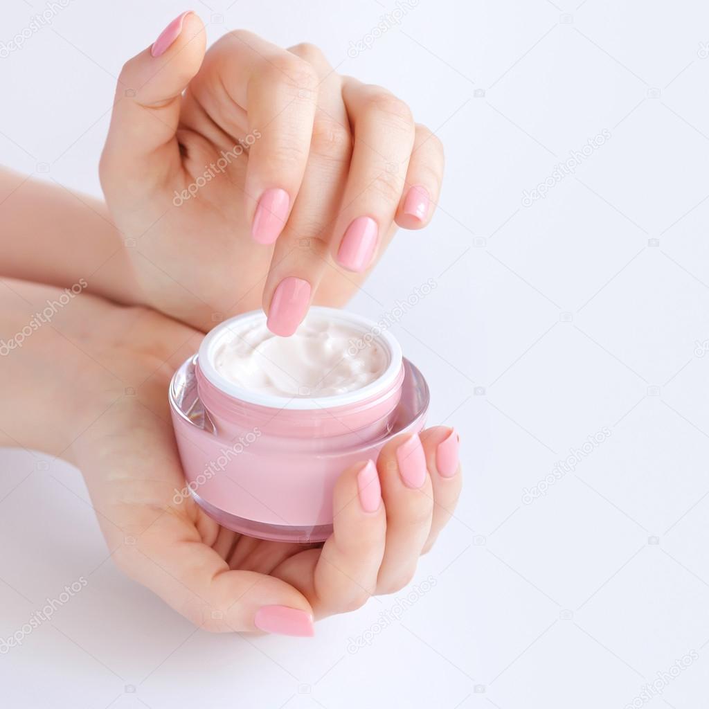 Hands of a woman with pink manicure with cream