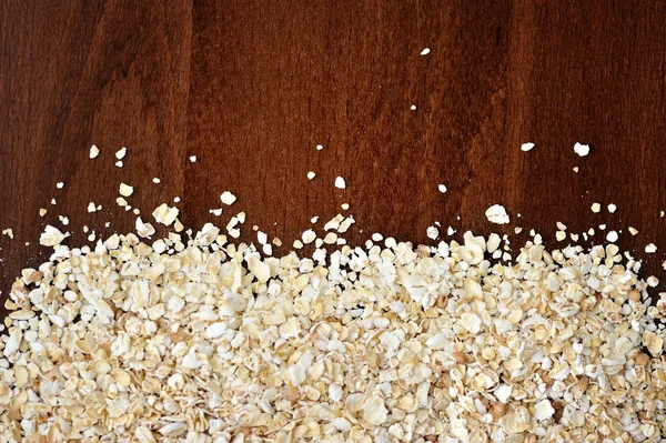 Close-up of oat flakeson dark wooden table as background or texture — Stock Photo, Image