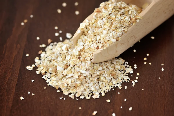 Copos de avena en cuchara de madera sobre fondo de madera — Foto de Stock