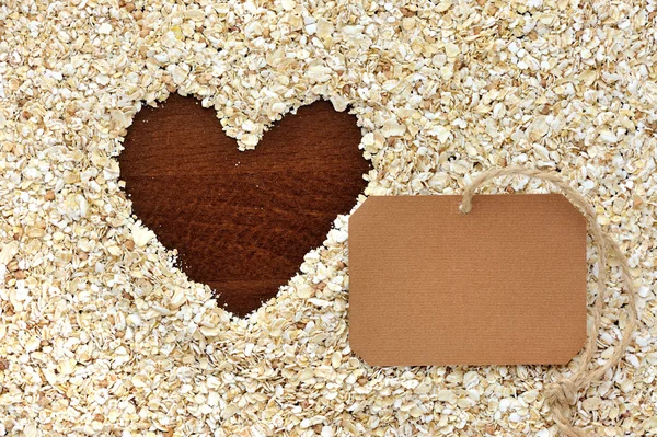 Frame of oat flakes in the form of heart and blank paper sticker — Stock Photo, Image