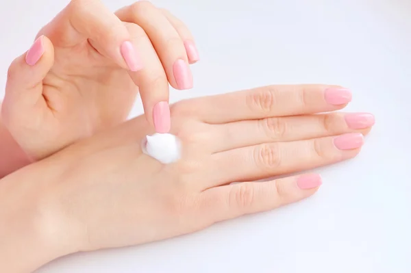 Giovane donna con manicure rosa applica crema sulle mani — Foto Stock