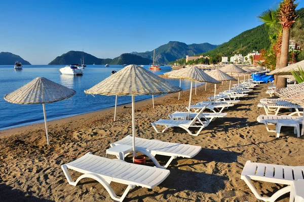 Plaj şemsiye ve şezlong mavi deniz ve dağ pitoresk defne fon karşı