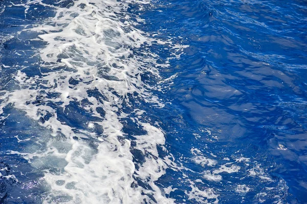 Blaue Meerwasseroberfläche in Bewegung mit Schaum — Stockfoto