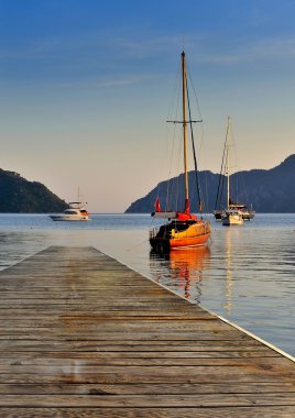 Gün batımında Yatlar ile defne deniz. Arka planda dağlar