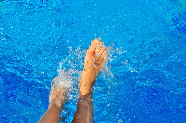Сексуальные женские ноги, плескающиеся в тропическом бассейне — стоковое фото