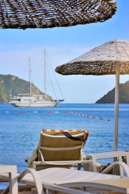 Plaj şemsiye ve şezlong tekneler ve deniz fon karşı