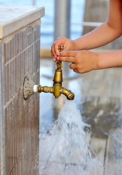 Close-up kid hands closes the faucet. Old grunge tap in garden — Stock Photo, Image