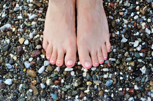 Mädchenbein auf bunten Kieselsteinen am Strand am Meer — Stockfoto
