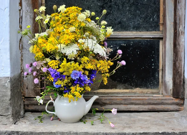 Schöner Strauß heller Wildblumen, die am Fenster stehen o — Stockfoto