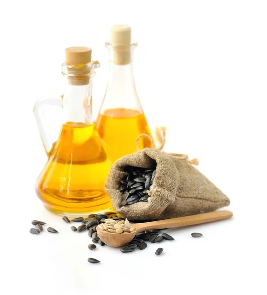 Wooden spoon with sunflower seeds on a background of small bag and a bottles of oil — Stock Photo, Image