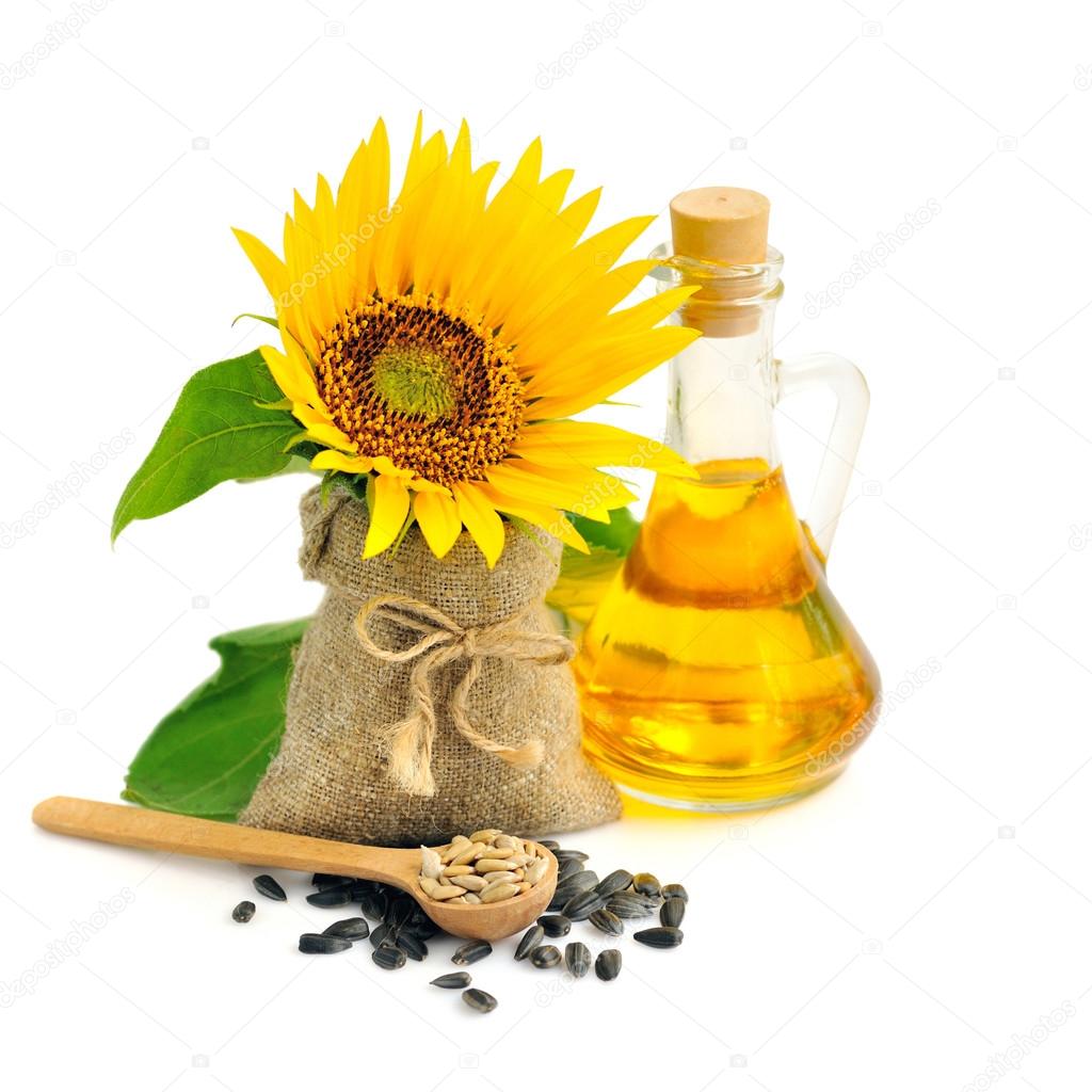 Wooden spoon with sunflower seeds on a background of small bag with flower and a bottle of oil