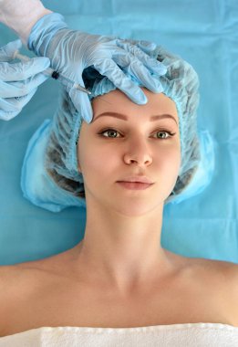 Kozmetik uzmanı güzellik salonunda güzel bir kadının yüzüne iğne yapıyor. Kozmetoloji kavramı.