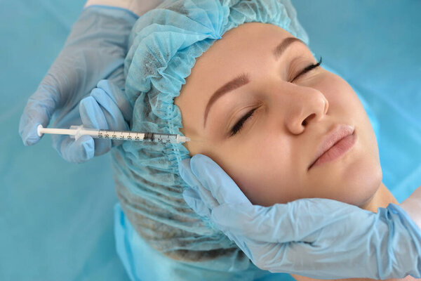 Cosmetologist does injections on the face of a beautiful woman in a beauty salon. Cosmetology concept.