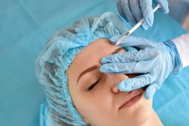 Kozmetik uzmanı güzellik salonunda güzel bir kadının yüzüne iğne yapıyor. Kozmetoloji kavramı.