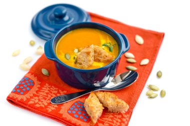 Kabak çorbası, beyaz arka planda kızarmış ekmek ve kabak çekirdeği..