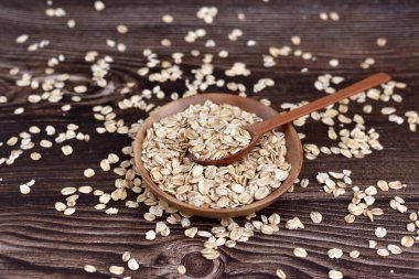 Tahta kasede pişmemiş yulaf gevrekleri. Koyu tahta bir masada kaşıkla. Sağlıklı beslenme kavramı