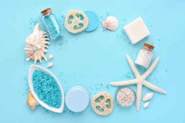 Deniz tuzu, krem, losyon, sabun, sünger ve kabuklar mavi arka planda spa için ayarlanmış. Spa konsepti. Metin için boşluk olan üst görünüm 