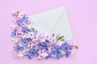 Pembe arka planda sümbül çiçekleri olan bir zarf. Düz yatış, üst görünüm.