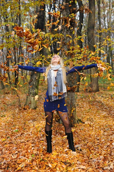 Mooie gelukkig vrouw spelen met herfst bladeren in bos — Stockfoto