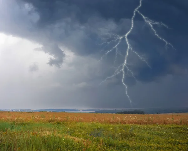 Gewitter mit Blitz auf Wiese. Dunkle ominöse Wolken. — Stockfoto
