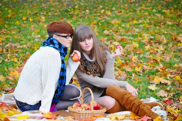 Young girls in the autumn park sitting on the grass — Stock Photo, Image