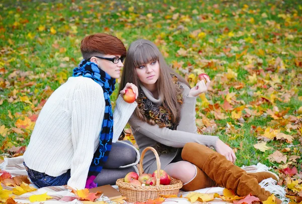 Young girls in the autumn park sitting on the grass — Stock Photo, Image