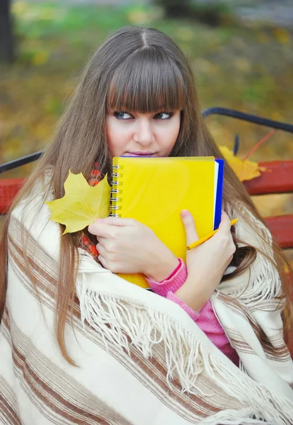 Hermosa joven está con un cuaderno en un parque — Foto de Stock