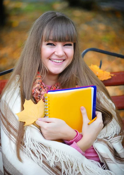Schöne junge Mädchen ist mit einem Notizbuch in einem Park — Stockfoto