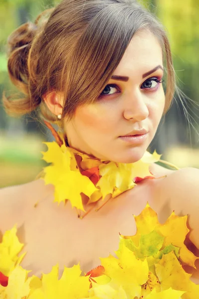 Portret van een mooie jonge vrouw in de herfst bladeren — Stockfoto